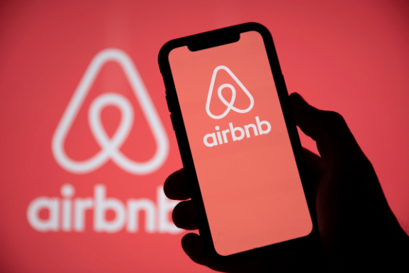 An Airbnb Logo on mobile and background